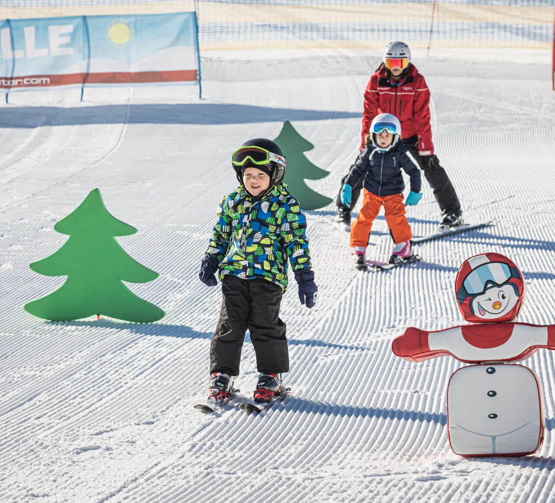 Kinder beim Skifahren in St. Johann in Tirol, mit Baumfiguren