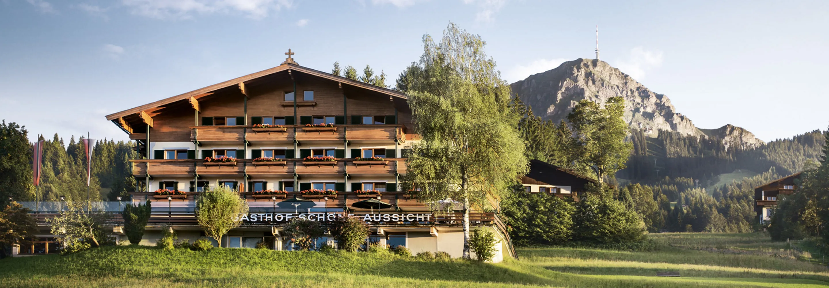 Alpenhotel mit Blick auf die Berge und grüne Wiesen.