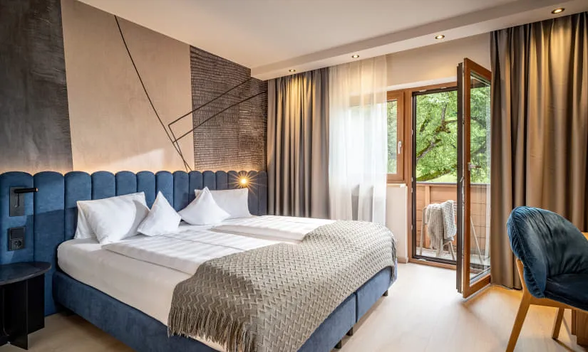 Helle Hotelzimmer mit zwei Betten und Balkonblick
