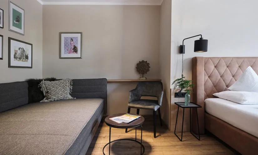 Modernes Zimmer mit Bett, Sofa und dekorativen Bildern.