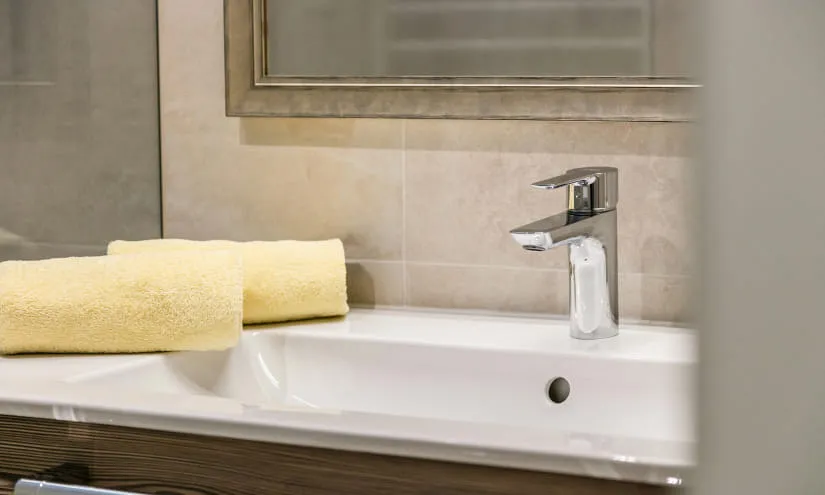 Badezimmer mit zwei gelben Handtüchern und einem Wasserhahn