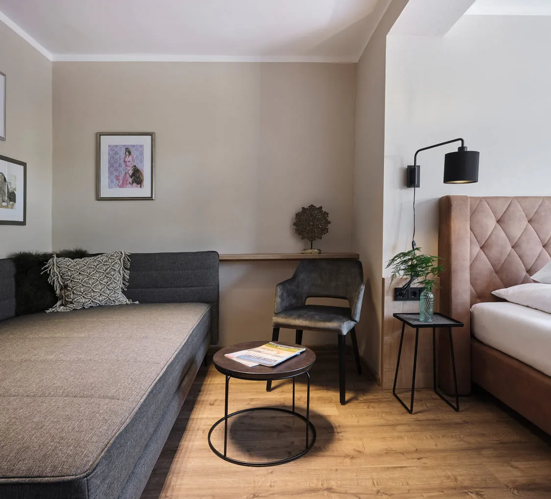 Helles Zimmer mit Sofa, Bett und dekorativen Bildern.