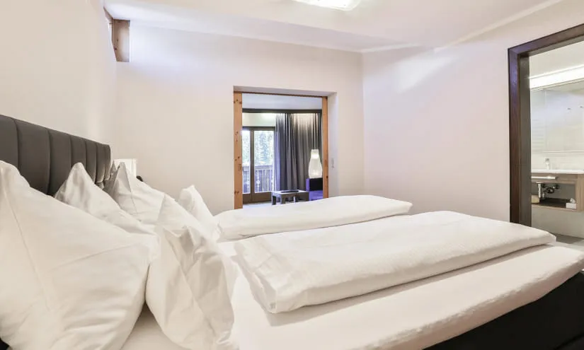 modernes Schlafzimmer mit zwei Betten und einem Badzugang