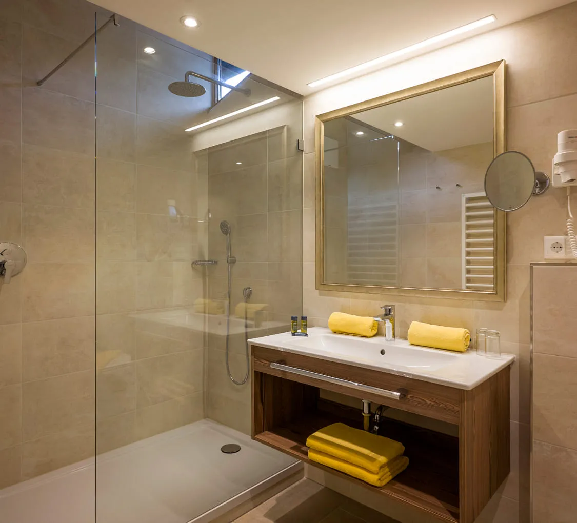 Moderne Badezimmeransicht mit Dusche und gelben Handtüchern