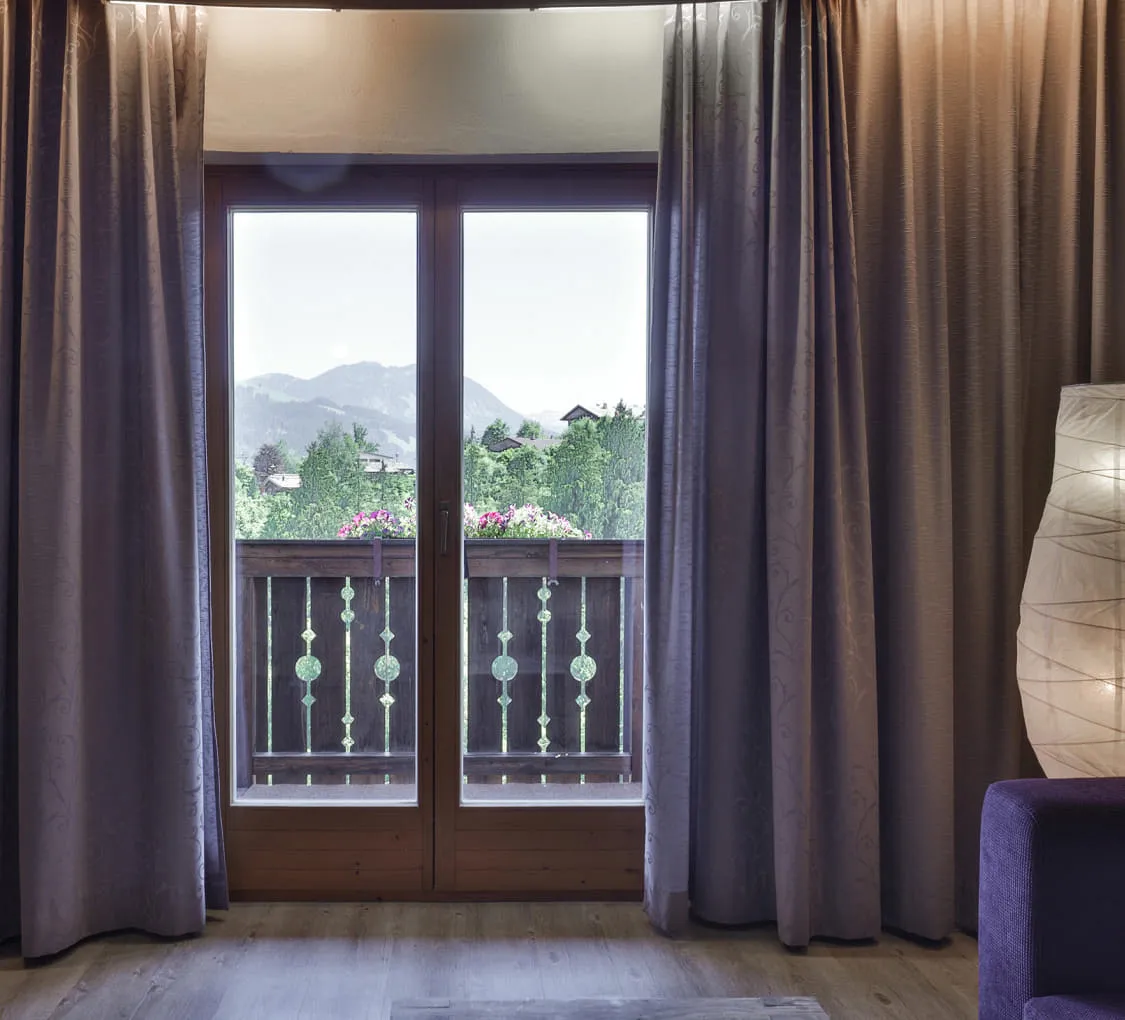 Fenster mit Vorhängen und Aussicht auf Berge und Balkon